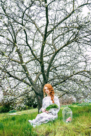 Portrait of a beautiful redhead girl in the spring gardenの写真素材
