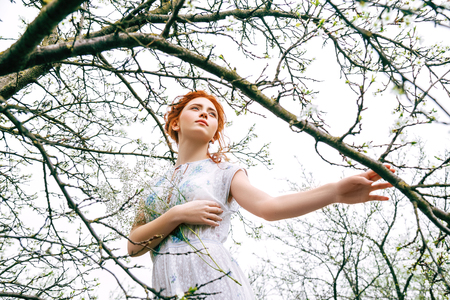 Portrait of a beautiful redhead girl in the spring gardenの写真素材
