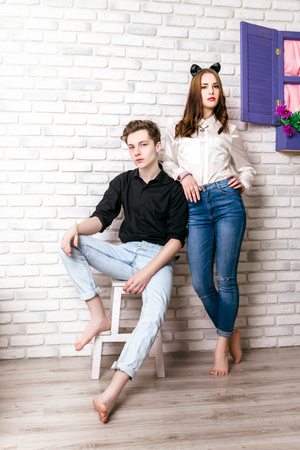 Stylish couple in the studio on a background of white brick wallの写真素材