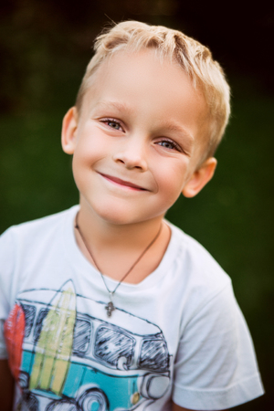 Portrait of a little smiling blond boy in a summer green gardenの写真素材