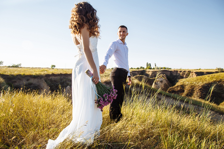 Beautiful couple in field, lovers or newlywed posing on sunset with perfect sky.の写真素材