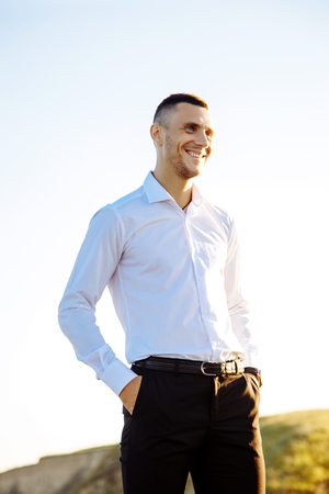 Cheerful young man athlete in white shirt standing near the seaの写真素材