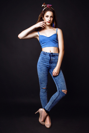Fashion photo of young woman on black background. Dressed in blue top and jeans. Girl posing. Studio photo.の写真素材