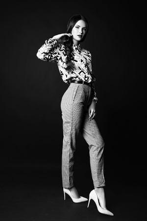Fashion photo of young woman on black background. Dressed in a shirt and pants with ornament. Black and whiteの写真素材
