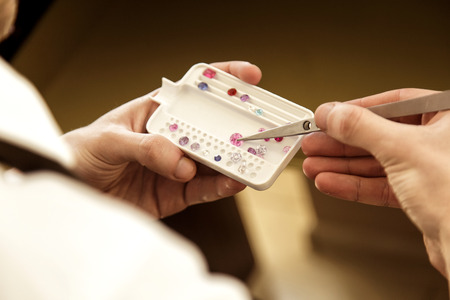 Hand of a man close-up of a pincer choosing a stone to create a future ringの写真素材