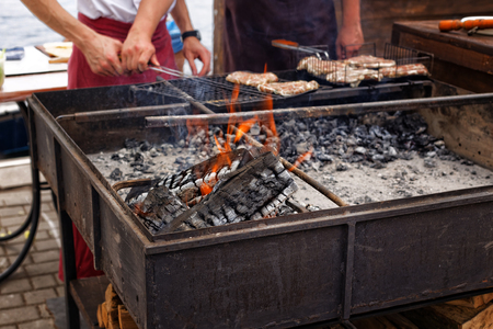 Festival of street food. Grill with burning firewood and sausages on the grill roasting outdoors in the local marketの写真素材