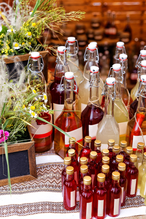 Festival of street food. Wooden counter with a variety of bottles with alcoholic and fruit drinks and homemade jams sold outdoors in the local marketの写真素材