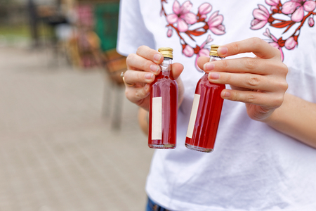 Festival of street food. A girl in a white T-shirt bragging about buying a drink holding small bottles in the open air in the local market.の写真素材