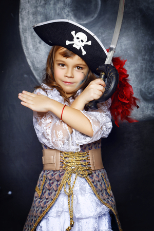 Little girl dressed in pirate costume on a black background with a moon image in a studio with Halloween decorationsの写真素材