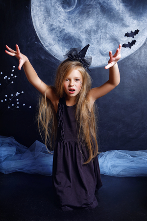 a little wicked witch with Shaggy hair on the background drawn in chalk Moon kneels and scares. The concept of Halloweenの写真素材
