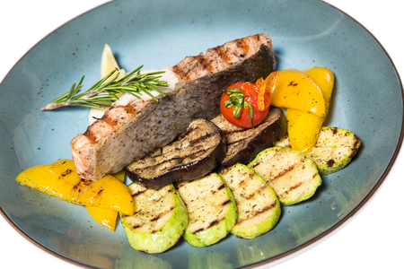 fried fish steak with bechamel sauce, lemon and fried vegetables on a blue saucer. Isolated on white background. Top viewの写真素材