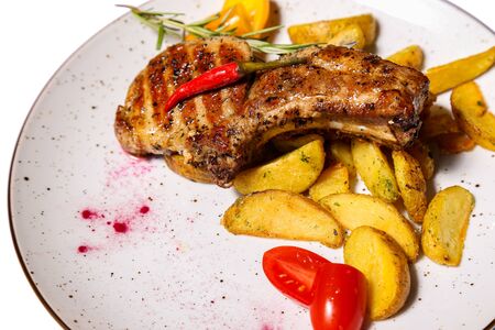 Steak with fried potatoes and tomato on a plate isolated on white backgroundの写真素材