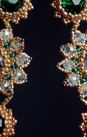 handmade jewelry made of beads in macro. earrings from white beads. earrings from stones. beautiful ornaments. earrings from golden beads. ornaments on a black backgroundの写真素材