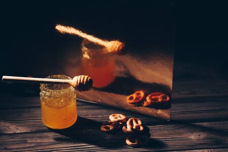 jar of honey with bagels on wooden table close up with honey dipper on black backgroundの写真素材