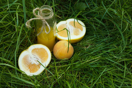 a bottle of homemade lemonade juice lies on the grass outdoors. Picnic on nature in the park against...