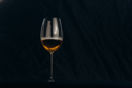 a glass of white wine on a black background. the smoke from the hookah envelops the glass. rest, holiday. alcoholic drink closeup. white fog in a glass. fog.の写真素材