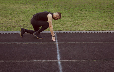 one man on the start line awaits the start of the sprint. stadium, rubber track. athletics...