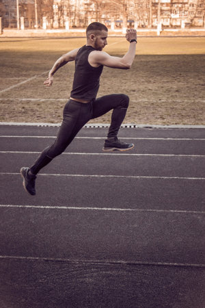 one caucasian male is doing a sprint start. running on the rubber track. Track and field runner in...