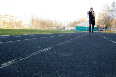 one caucasian male is doing a sprint start. running on the rubber track. Track and field runner in...