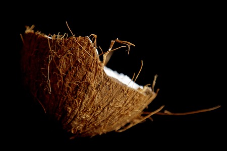 ripe coconut is broken into two halves isolated on a black background close-up. the insides of the tropical palm fetus.の写真素材