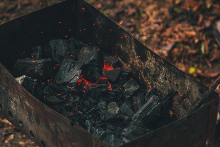 charcoal smolder in the iron grill. cooking picnic outdoors. sparks over the embers top view close up.の写真素材