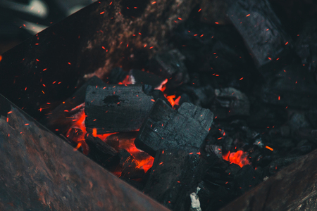 charcoal smolder in the iron grill. cooking picnic outdoors. sparks over the embers top view close up.の写真素材
