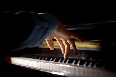 one male hand on the piano. The palm lies on the keys and plays the keyboard instrument in the music...