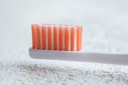 new orange-bristled toothbrush head close-up on a white table. subject of personal hygiene face close-up on a blurred background.の写真素材