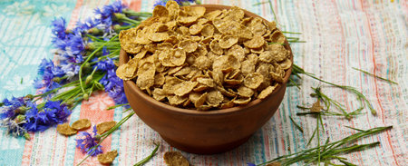 Sugarcorn flakes in a ceramic bowl closeup top view. light breakfast scattered on the table with...