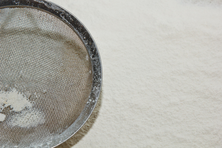 Flour and manual flour sieve on a white kitchen table. Top view. Close-up. Copy space. cooking dough. metal kitchen appliance.の写真素材