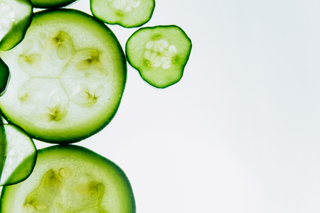 green translucent slices of cucumber on the background of bright white light close-up. transparent discs of vegetables. texture of kaleidoscope patterns in macro.の写真素材