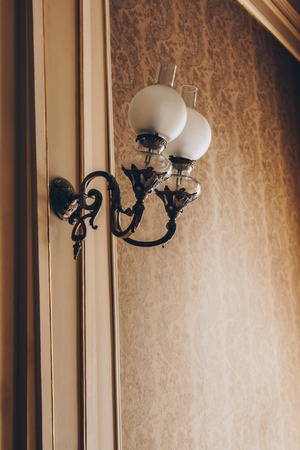 Wall sconce on the wall with vintage beige wallpaper. interior room with luxury decorations and lamps.の写真素材