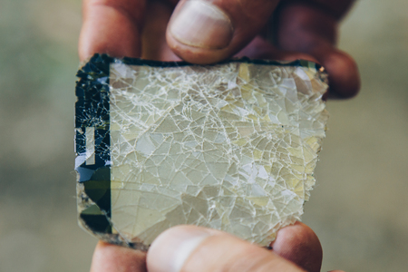 men's hands are holding cracked glass from a smartphone close-up on a blurred background. broken protection on the phone screen in macro copy space.の写真素材