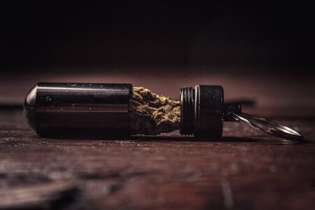 storing cannabis cones in a keychain container in the form of a bullet close-up. carrying and storing legalized soft drug in pocket crisper.の写真素材