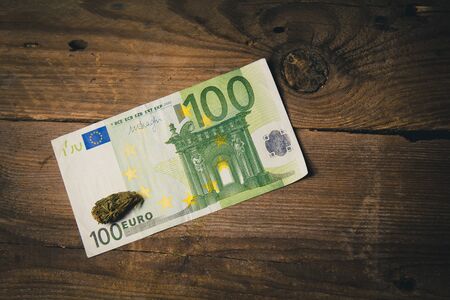 a cannabis bud lies on a hundred euro bill close-up. purchase and sale of legalized soft drugs. medical cannabis business concept.の写真素材