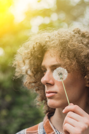 portrait of a young curly-haired guy in a summer park on the street. student and young traveler...