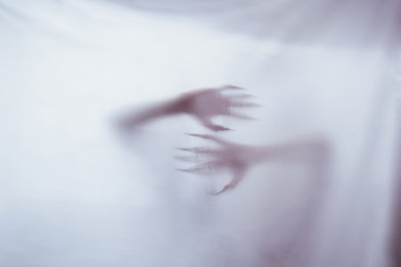 silhouette of a female sexual figure behind foggy glass. concept of the spirit of poltergeist from the other world. frightening hands of death through the fabricの写真素材