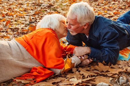 Close up portrait of a happy old man kissing his wife's hands. In the park in autumn foliage a happy...