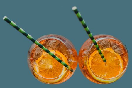 Aperol alcoholic drink with ice cubes in a glass and an eco-friendly cardboard tube. Popular cocktail, bar menu, orange liquidの写真素材
