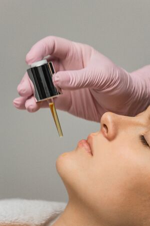 preparation for procedures in the cosmetologist s office. applying oil to moisturize the face with a special pipetteの写真素材