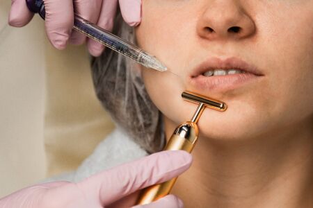 contour plastic. A cosmetologist injects a botulinum toxin to tighten and smooth out wrinkles on the skin of a female faceの写真素材
