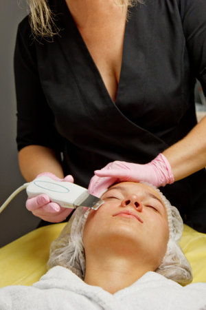 close-up. Ultrasonic face cleaning. Modern equipment. Beautician does cosmetic procedure on woman...