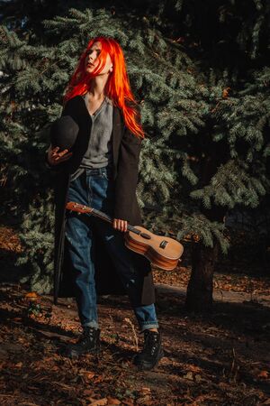 Sexy redhead girl with long hair plays the ukulele. Perfect woman portrait. Gorgeous strong and thick hair. Deep blue eyes. Natural beauty, clean skin, face and hair careの写真素材