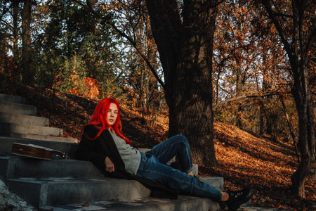 Sexy beautiful redhead girl with magnificent long hair. Ukulele playing, sitting on the steps in the...