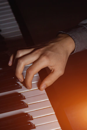one male hand on the piano. The palm lies on the keys and plays the keyboard instrument in the music...