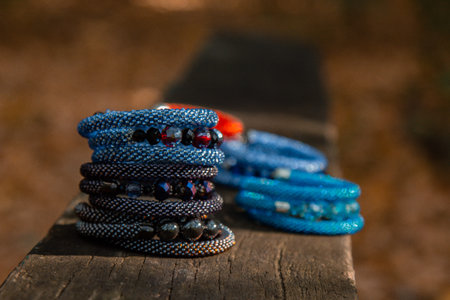 Beautiful, shiny, colorful bracelet set with large beadwork beads. On a wooden bench in the park. Jewelry on handの写真素材