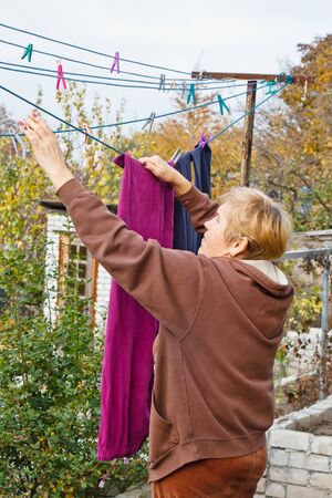 Laundry woman hangs clean wet cloth on clothes dryer after washing at home. Household chores and housekeepingの写真素材