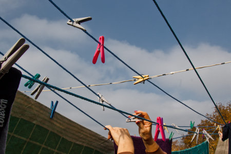 A clothespin hangs on the washing line. A rope with clean linen and clothes outdoors on the day of...