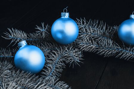 Christmas or New Year toy decorations golden balls and fur tree branch rustic on wooden background, top view, copy space. Color of the year 2020 classic blue. Fashionable pantone color trend conceptの写真素材