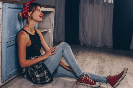 Portrait of a stunning smiling girl with red lips, dressed in a checkered red shirt and a bandana on...